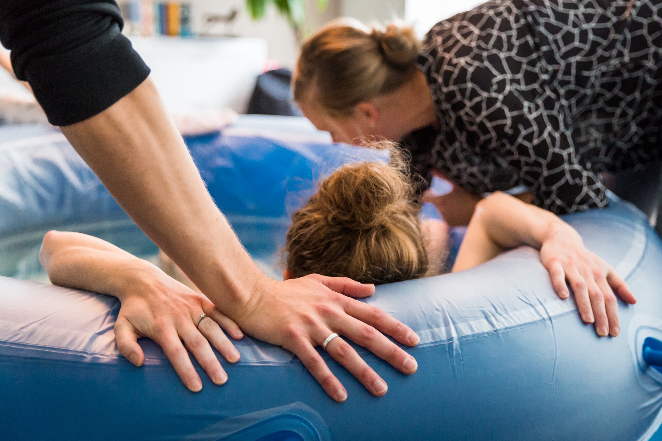 Mutter mit Hebamme und Partner am Geburtspool